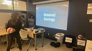 Students throwing ball in basket in classroom