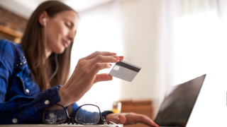 Woman holding a credit card and entering information in a laptop.