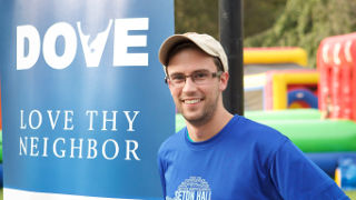 Dove student on the Green in front of a sign that says 