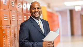 Photo of person smiling, holding booklet in their hands in front of a locker