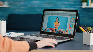 Photography student editing picture on retouching software, working on laptop for online design production class.