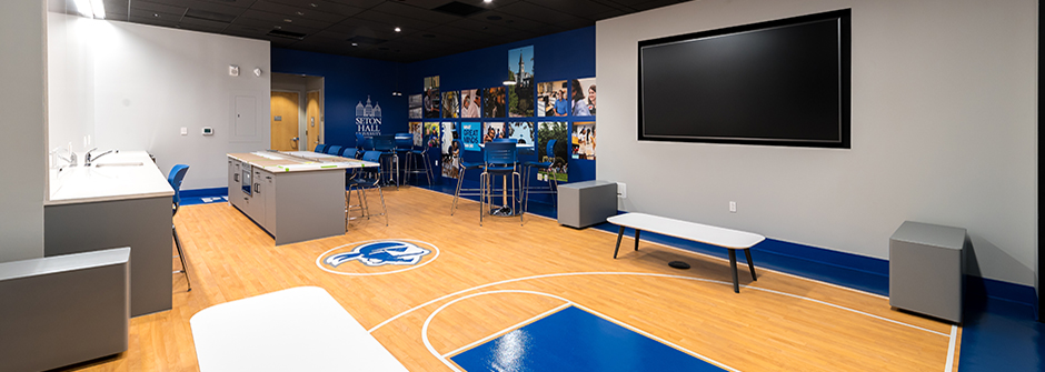 Tables, chairs, television in wall, wall graphics and floor designed like basketball court at the Gateway Center in Newark, NJ.