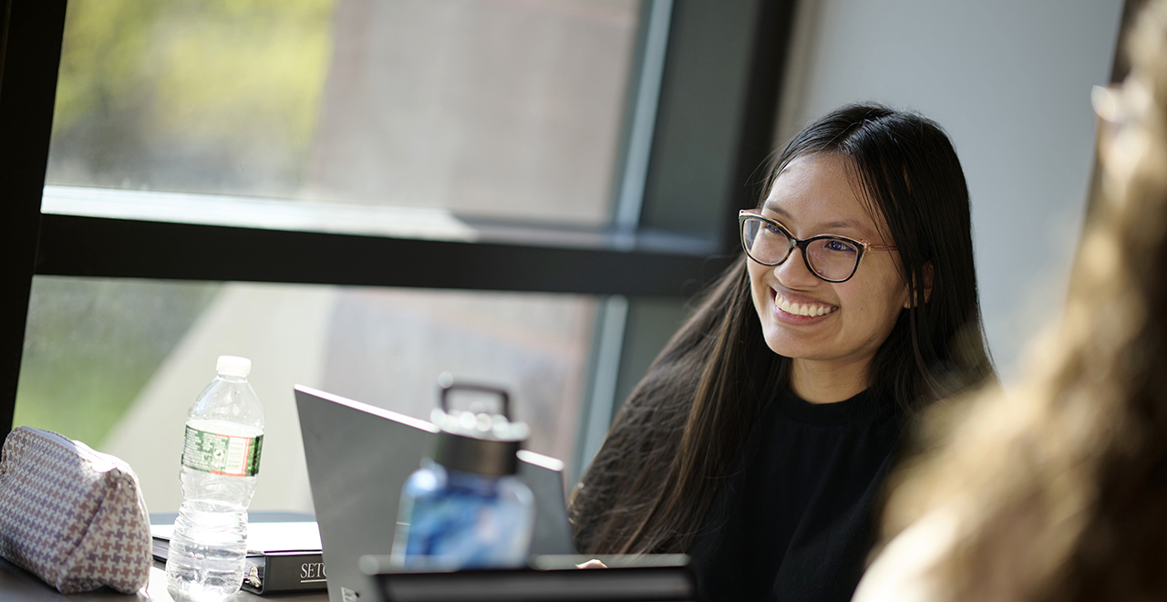 A photo of a graduate student in a classroom near a window.