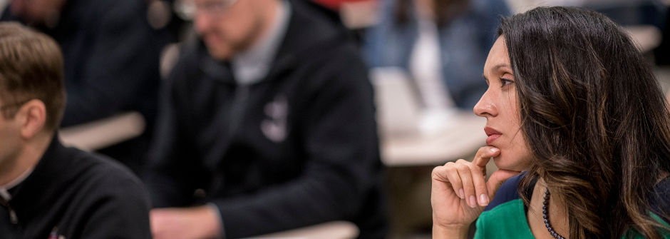 A student listening in class with her hand on her chin.