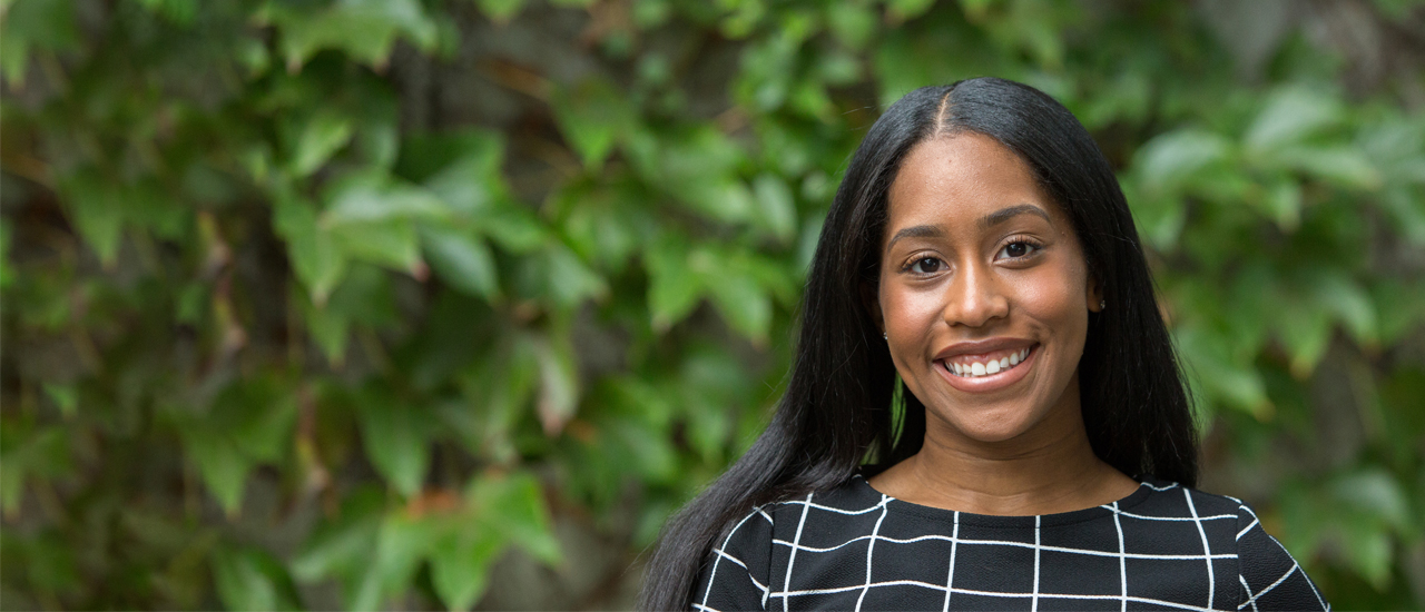 A female graduate student smiling outside. 