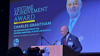 grantham on a podium with a screen displaying 