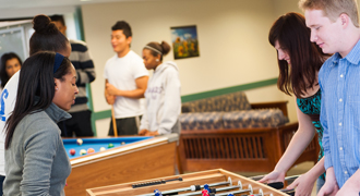 Students playing foos ball in a dorm. 