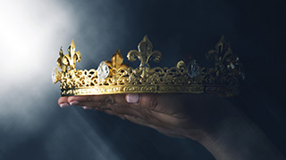 A hand holding a crown.