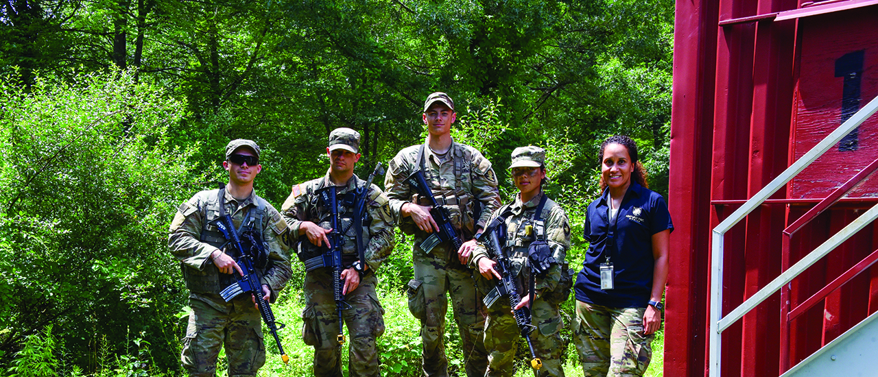 Military personnel in the woods with a robotic dog.