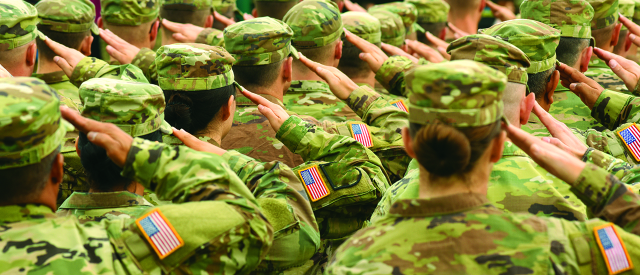 A group of military personnel in formation wearing uniforms and saluting.