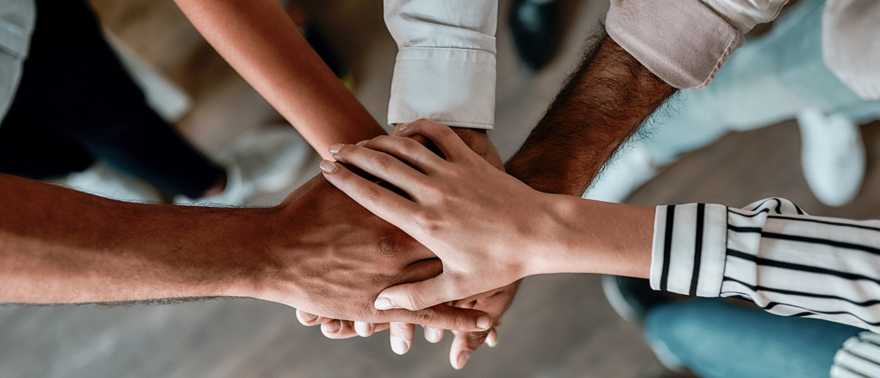 A group of people with their hands overlapping in the middle.