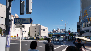 Four people are waiting to cross the street in Tokyo, Japan. The four people are facing away from the camera, backs in the photo.