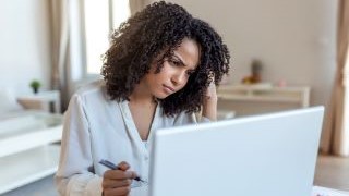 student with a concerned look on her face sitting in front of a laptop. 