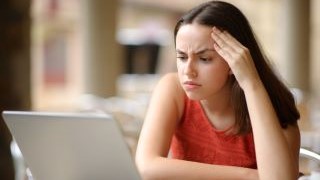 Student sitting in front of a laptop with a concerned look on her face.