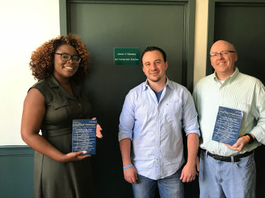 Three members of the Editorial team holding up the last hard copy of the Journal of Diplomacy.