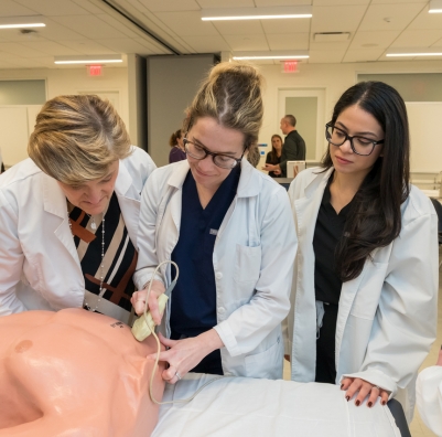 Two nursing students working with a training dummy