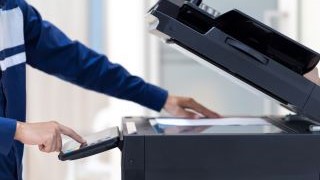 Student pressing button on panel of networked printer.