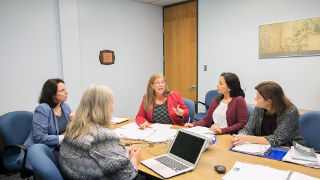 Women sitting around a table talking. 