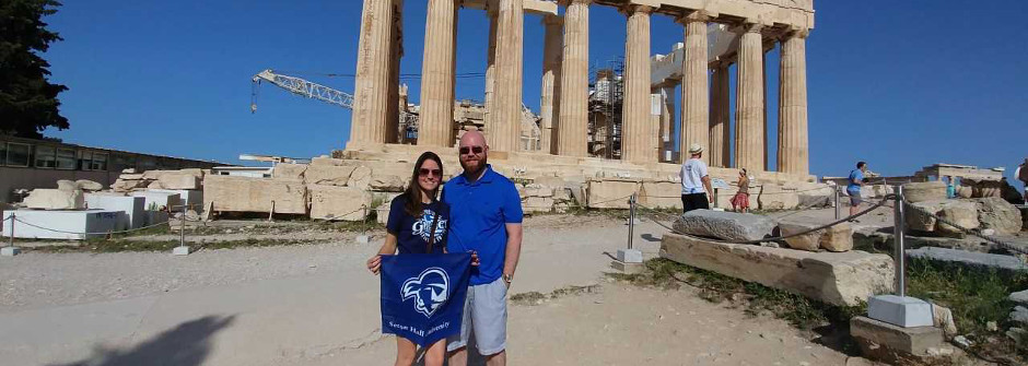 Tanya (Paitakes '05) and Garry De Boer '05 hold up the Seton Hall Pirate Bandana in front of ancient ruins. 