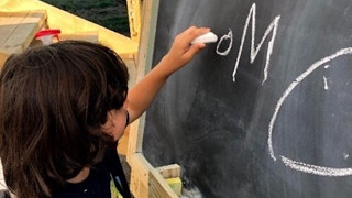 A photo of a young boy drawing on a board.