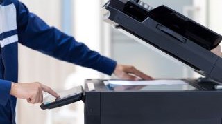 Student pressing button on panel of networked printer.