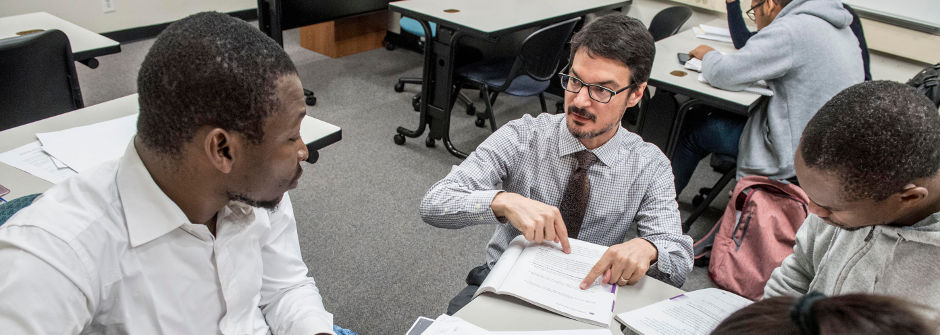 Professor Brian Meadows working with students at eye-level. 