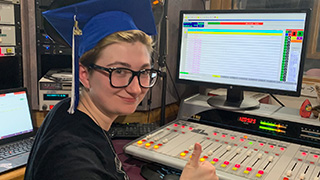 student in booth with graduation cap