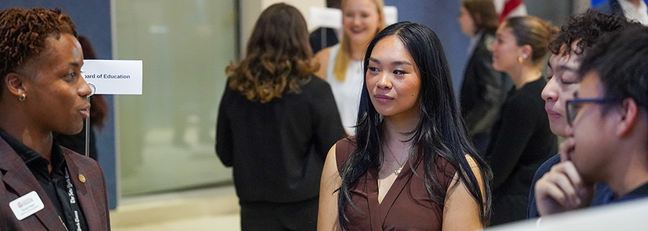 A speaker conversing with three students at the Career Fair.