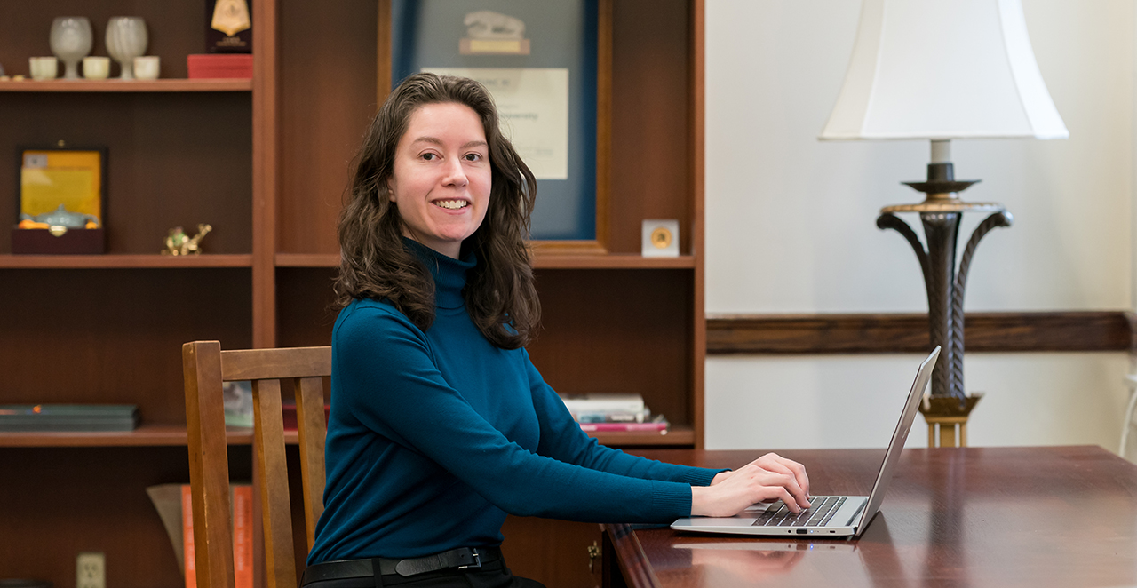 Sarah Dimichino sitting at a desk working on a laptop