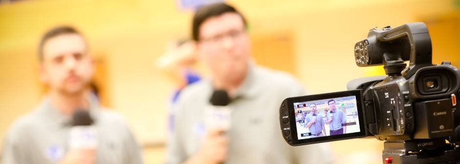 Two students on camera commentating a sports game. 