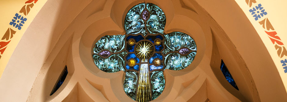 An image of a stained glass window in the shape of a cross.