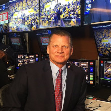 Man smiling for a photo with monitors in the background