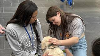 Student leaders play with a dog named Blue.