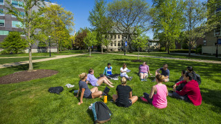 Students sitting on grass in a circle.