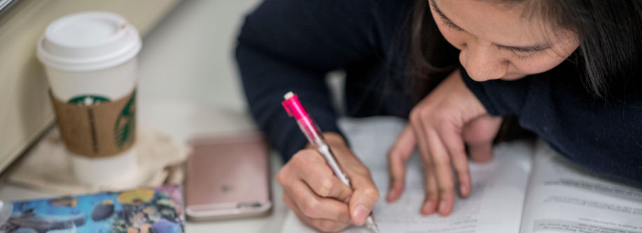 Student writing in a workbook. 