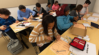 A group of students practicing suture skills. 