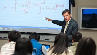 Students in a classroom listening to a professor teach a lesson.