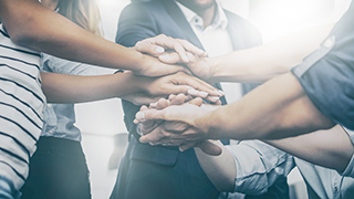 A team of people standing together stacking hands symbolizing teamwork.