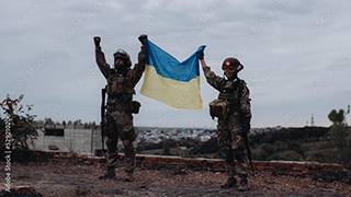 Two soldiers holding up the Ukrainian Flag