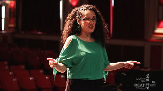 Professor Angela Kariotis Kotsonis speaking with actors on stage. 