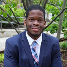 Image of Digital Comm. student Wilnir Louis outside in a suit.
