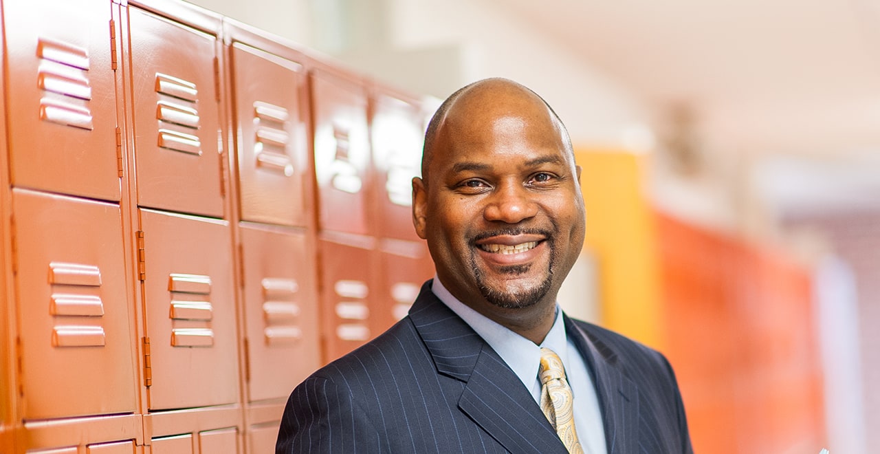 Photo of person smiling, holding booklet in their hands in front of a locker