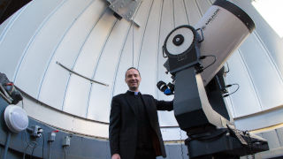 Joseph R. Laracy next to telescope 