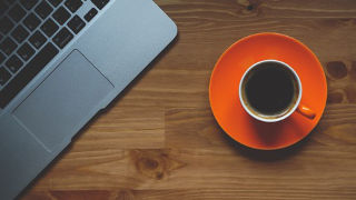 An image of a coffee mug next to a laptop.