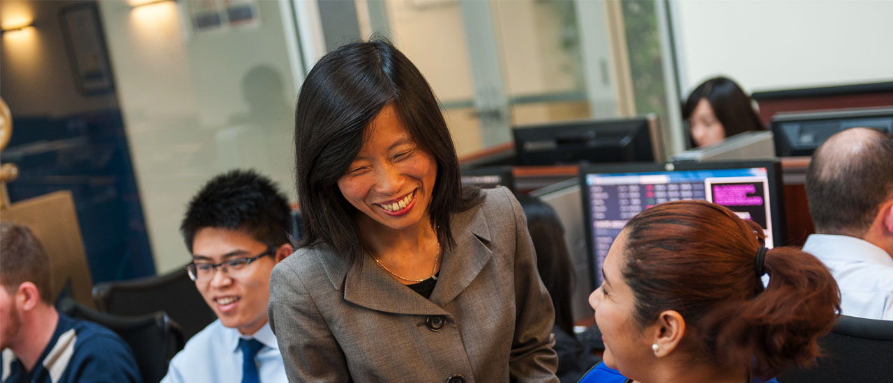 Eleanor Xu in Trading Room with two students 