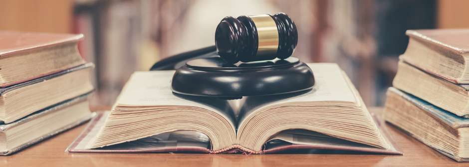 An open book, in a library, with a gavel resting on top. 