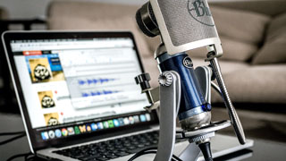 A laptop and microphone set up for use in a podcast.