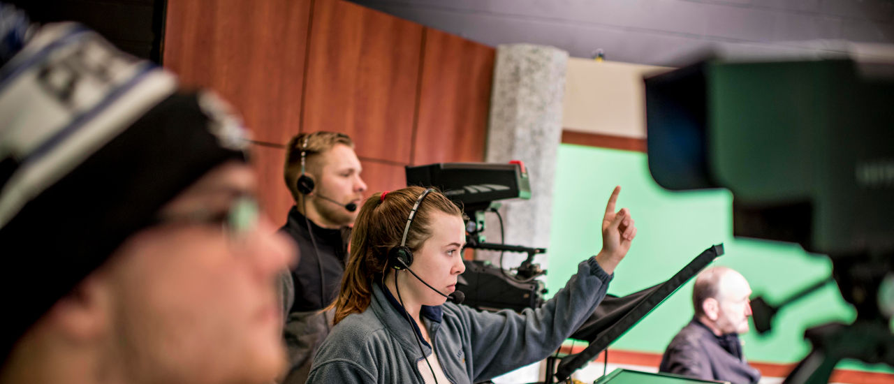 Students in the TV Production studio directing a show with headsets and cameras. 